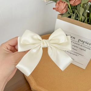 Detailed view of elegant creamy white satin ribbon hair clip with double-layer bow design