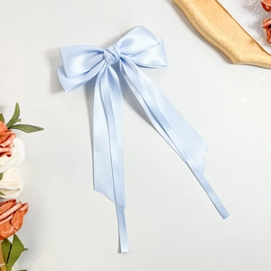 Close-up of light blue satin ribbon hair clip with elegant double-layered bow design