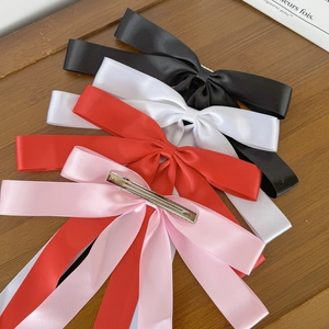Elegant satin bow hair clips with long streamers in four colors on a wooden surface