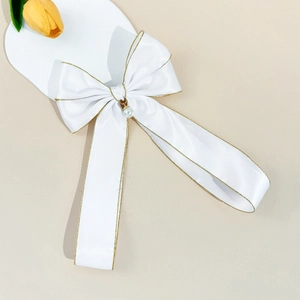 Barrette nœud en satin blanc avec bordure dorée et perle pendante sur support cœur