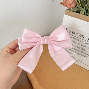 Detail of pink satin bow hair clip with high-density silk shine and layered structure