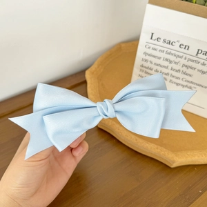 Detail view of light blue satin double bow hair clip with French minimalist design