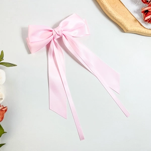 Detail of pink satin bow hair clip with long ribbons and elegant silk luster