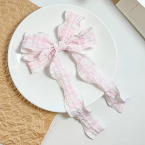 Dettaglio del fermaglio per capelli a fiocco rosa e bianco con trama a pieghe e nastri