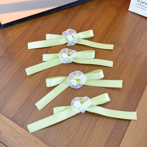 Dettaglio di quattro fermagli per capelli a fiocco verde chiaro con rose in rete