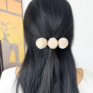 Detail of cream satin rose hair clip styled on a half-up hairstyle for women