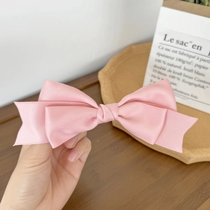 Close-up of pink satin double-layered bow hair clip with elegant silky texture