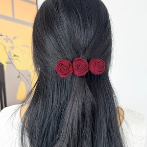 French vintage red satin triple rose hair clip elegantly styled on dark wavy hair
