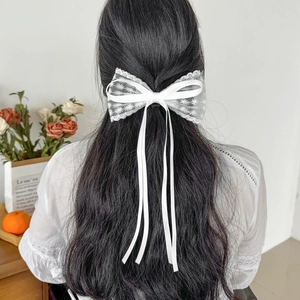 Eleganter weißer Spitzen-Haarclip mit langen Bändern auf dunklem Haar gezeigt