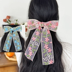 Dettaglio di fermagli per capelli con fiocco in pizzo e ricami floreali rosa e blu