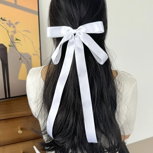 Elegant white satin ribbon bow hair clip shown on back of head with long streamers
