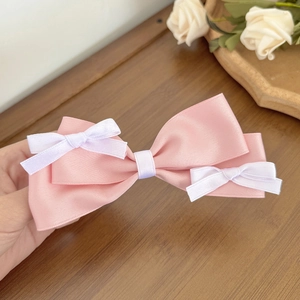 Close-up of pink satin layered bow hair clip with small white ribbon detail