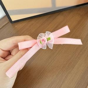Dettaglio di un fermaglio per capelli in nastro di seta rosa con rosa di stoffa