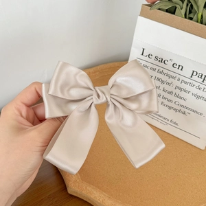 Detail of elegant champagne gold satin bow hair clip with a silky smooth fabric texture