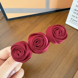 Detail of three handmade dark red satin fabric roses on a vintage style hair clip