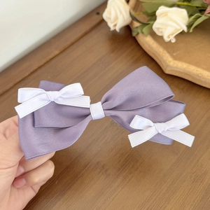 Detailed texture of layered lilac satin bow hair clip with white mini bow accents