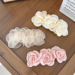 Barrettes à cheveux à fleurs camélia en satin blanc, beige et rose sur fond de bois