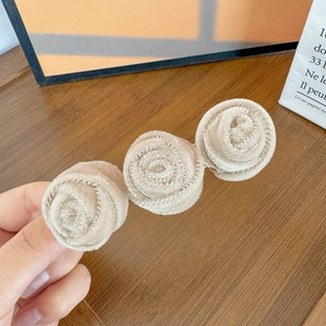 Detailed macro view of beige chenille fabric 3D rose flowers on a French vintage hair clip