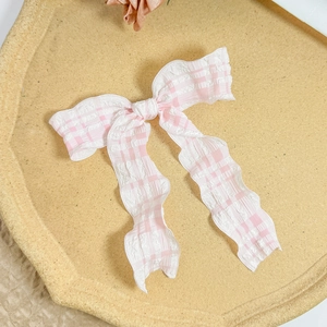 Detailed texture of a pink and white checkered ribbon bow hair clip with soft fabric pleats