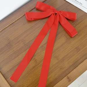 Detailed macro view of the silky red satin bow hair clip with elegant long ribbons