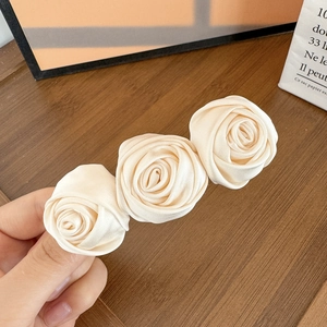 Close-up of three cream satin rose flowers on a French vintage style hair clip