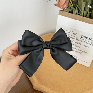Detail shot of multi-layered black satin bow hair clip with fine ribbed fabric texture