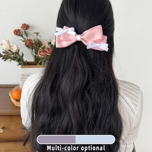 Pink and white layered satin bow hair clip on long wavy black hair for women