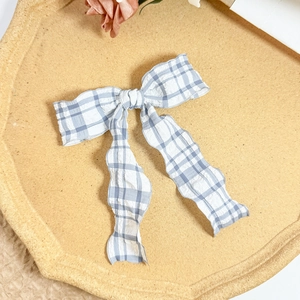 Detail of blue and white checkered bow hair clip with seersucker fabric texture