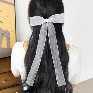Elegant white mesh bow hair tie with long streamers worn on model's long hair