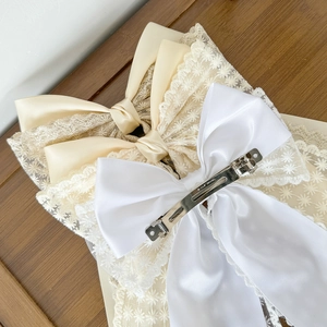 Elegant white satin and champagne lace bow hair clips for women set on wood