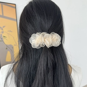 Vue détaillée de la pince à cheveux avec trois fleurs en organza champagne sur cheveux