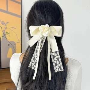 Elegant floral lace bow hair clip with long ribbons and a white rose on dark hair