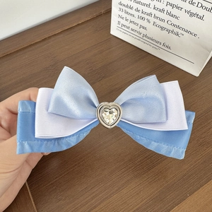 Detailed close-up of a three-layer blue ribbon hair clip with a sparkling heart rhinestone