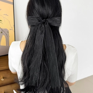 Detail view of a black bow hair tie with long ribbons and crinkled texture fabric