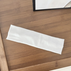 Close-up of a white elastic sports headband on a wooden tray for yoga and fitness