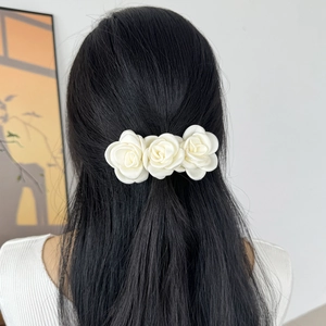 Détail de trois roses en tissu blanc crème disposées sur une barrette à ressort