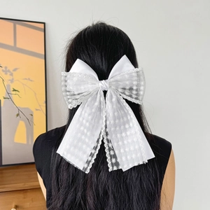Detail of a white lace bow hair clip with daisy embroidery on long black hair
