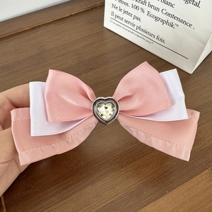 Close-up of pink and white layered satin bow hair clip with heart crystal center