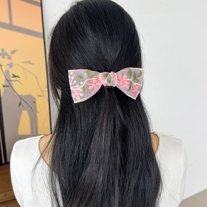 Dettaglio del fermaglio per capelli a fiocco in pizzo ricamato su capelli neri