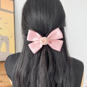 Elegante fermaglio per capelli in seta rosa con fiocco e rosa su capelli neri