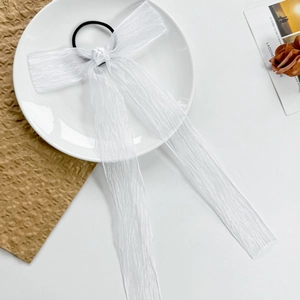Close-up of elegant white mesh bow hair tie with long streamers on a white decorative plate