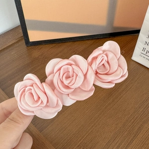 Vue détaillée de trois roses en satin rose faites à la main sur une barrette à cheveux