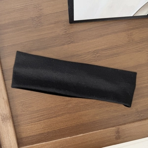 Detail showing high-elasticity black wide hairband on a textured wooden tray