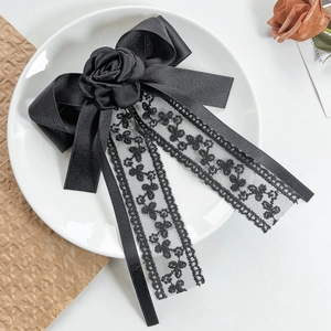 Detail of black lace ribbon hair clip with rose decoration on ceramic plate