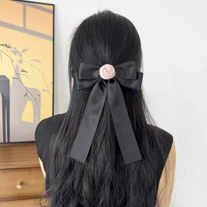 Gros plan d'un nœud papillon en satin noir avec rose rose sur les cheveux