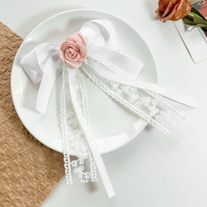 Detail of white lace ribbons and pink fabric rose on a soft bow hair clip