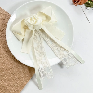 Detail of elegant cream bow hair clip with camellia flower and lace ribbons
