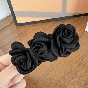 Détail de trois fleurs de camélia en satin noir sur une pince à cheveux effet soie