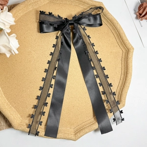 Detail of a large double-layer black satin bow hair clip with heart lace trim and mesh