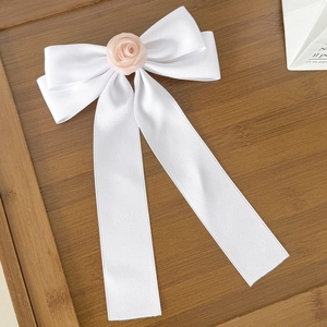 Détail d'un nœud en satin blanc avec une rose en maille rose et de longs rubans